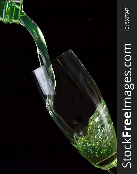 Glass of drink poured on black background