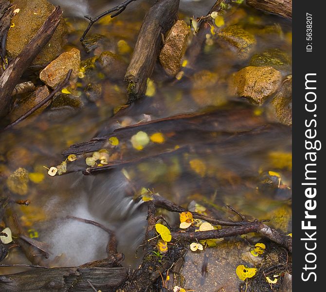 Autumn image of water, wood, stone, and leaves in a close up image of a stream in the Colorado Rockies. Autumn image of water, wood, stone, and leaves in a close up image of a stream in the Colorado Rockies.