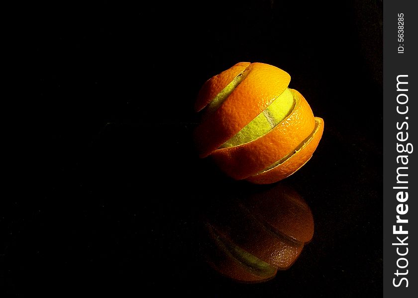 A tennis ball in the orange peel on a black background. A tennis ball in the orange peel on a black background