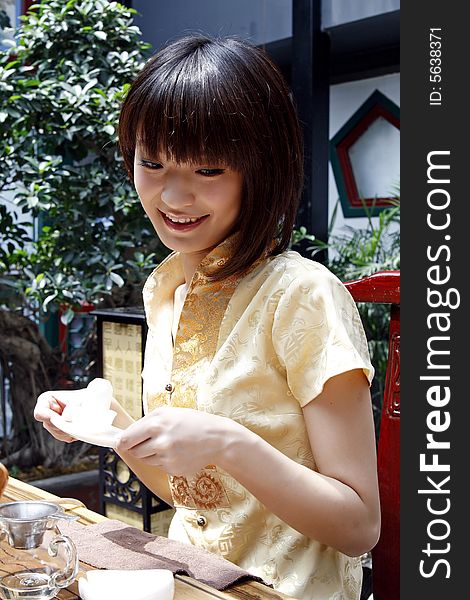 A beautiful Chinese girl is performing tea art in an ancient garden. Chinese characters on the lantern are the ancient poesy of China by the tree. A beautiful Chinese girl is performing tea art in an ancient garden. Chinese characters on the lantern are the ancient poesy of China by the tree.