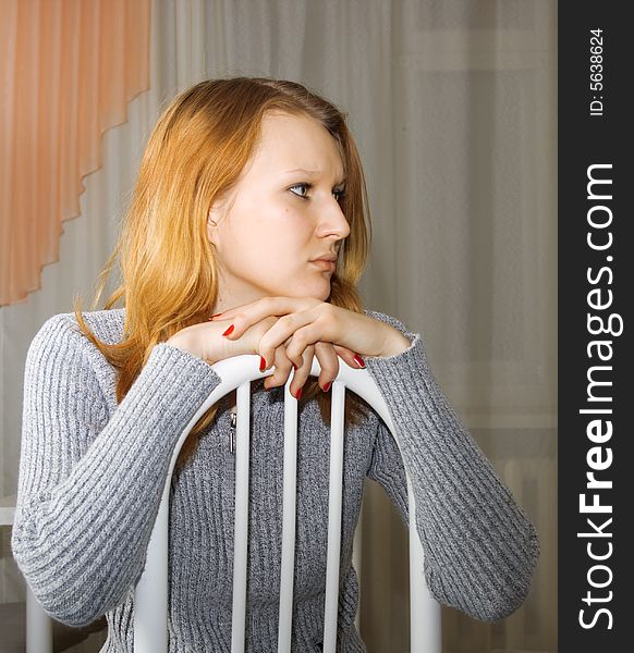 Portrait of the sad young girl sitting on a chair. Portrait of the sad young girl sitting on a chair