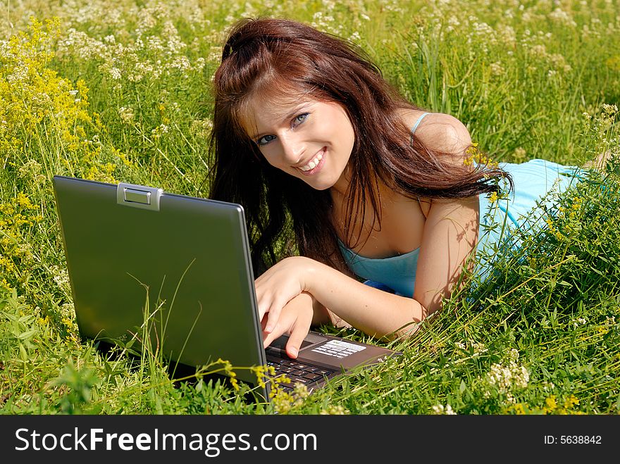 Young beautiful woman smiles while having fun with her laptop. Young beautiful woman smiles while having fun with her laptop.