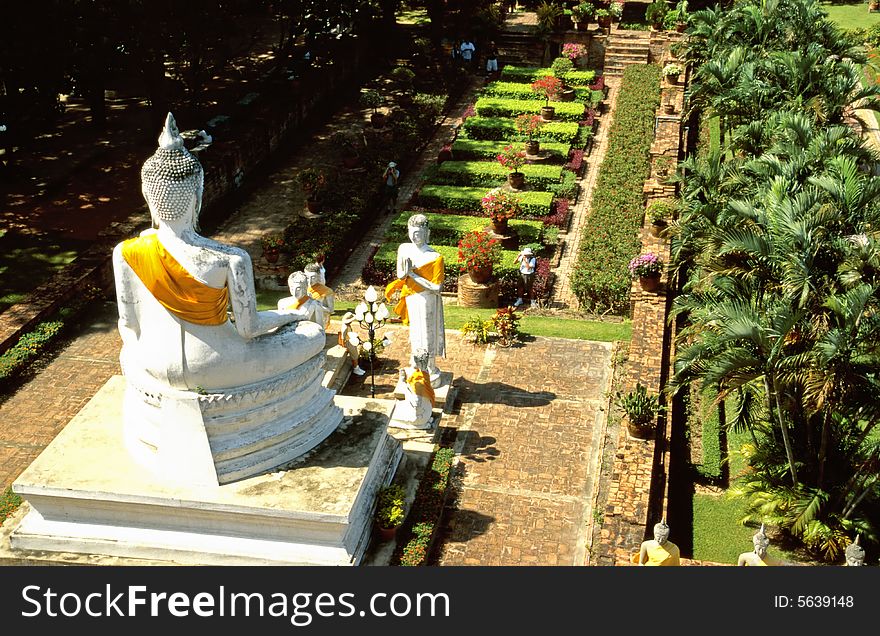 Row of Buddha statues with yellow and orange cape in Ayutthaya History Parc