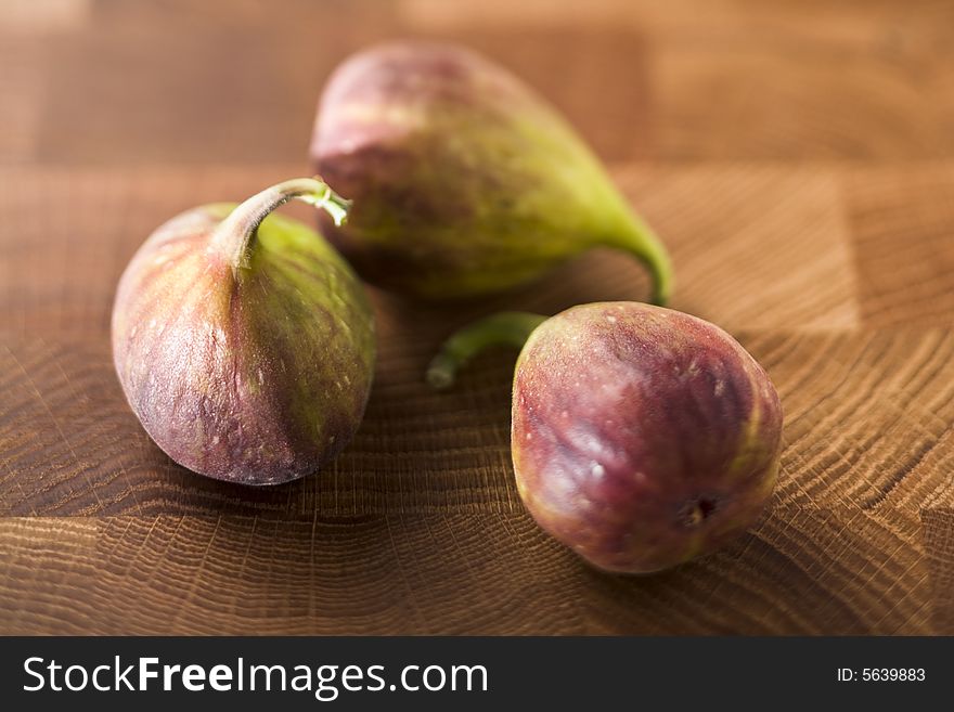 Three figs on oak wood surface - selective focus