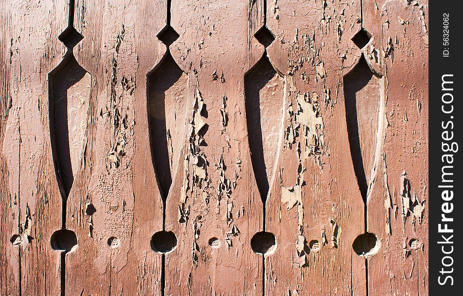 Old brown painted boards with cracked paint and carved patterns outside closeup. Old brown painted boards with cracked paint and carved patterns outside closeup