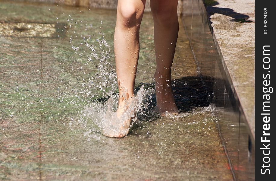 Girl's feet playing in the fountain closeup on summer day. Girl's feet playing in the fountain closeup on summer day