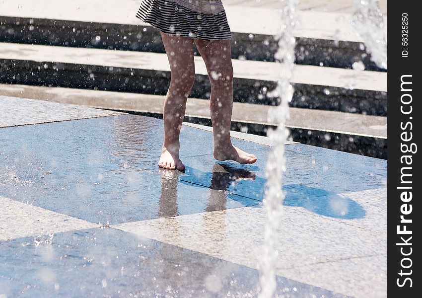 Girl s feet in gray skirt playing in the fountain