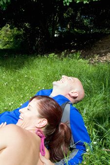 Couple Sitting On The Grass Laughing  - Vertical Royalty Free Stock Images