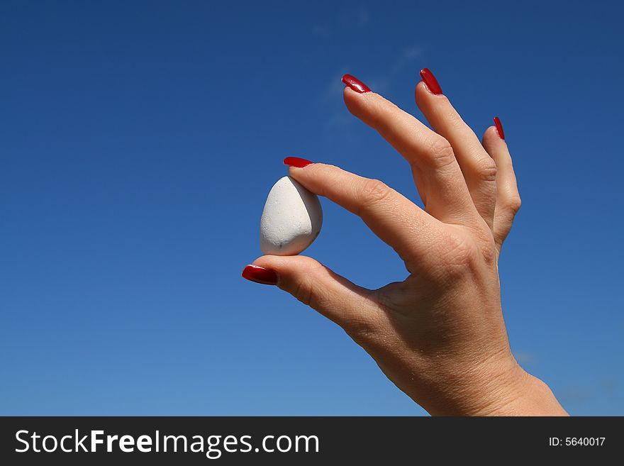 Lady with red nails holding a white stone up in the sky. Lady with red nails holding a white stone up in the sky