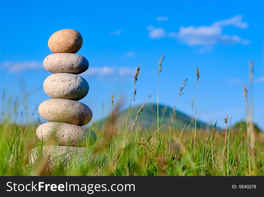 Round stones lays on a grass. Blue sky on a background