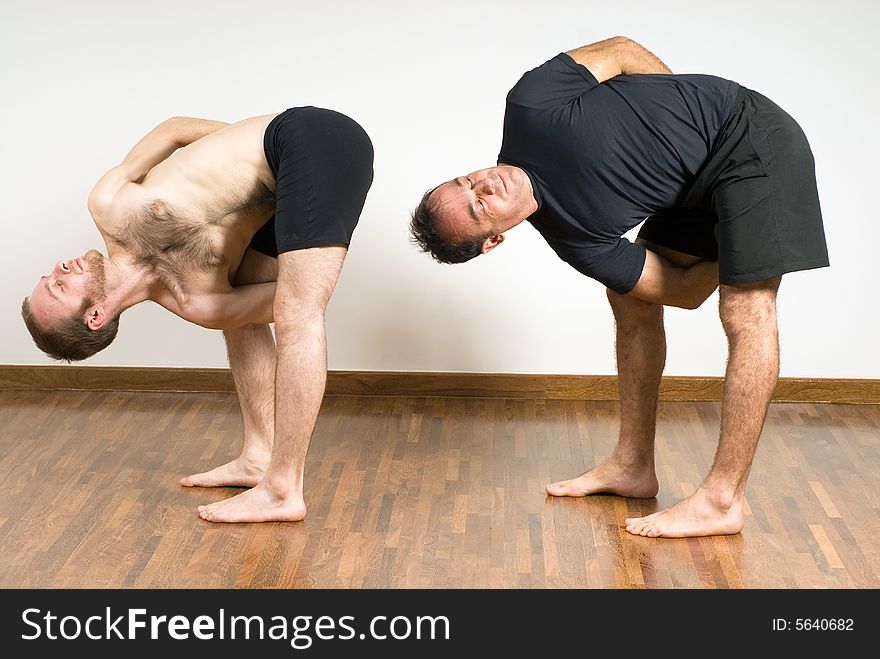 Two men practice yoga together. Horizontally framed photograph. Two men practice yoga together. Horizontally framed photograph