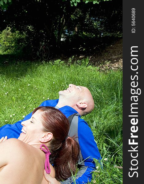 Happy couple sit on the grass and laugh in the park. Vertically framed photograph. Happy couple sit on the grass and laugh in the park. Vertically framed photograph