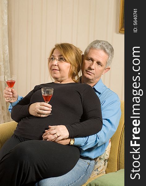 A woman sitting on a man's lap.  They are drinking wine and she is smiling. Vertically framed shot. A woman sitting on a man's lap.  They are drinking wine and she is smiling. Vertically framed shot.