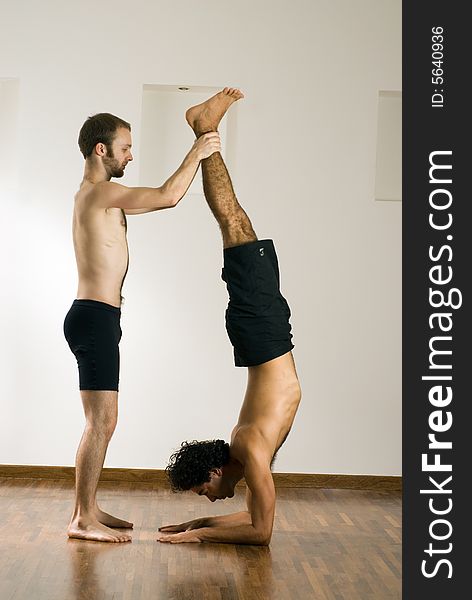 One man is balancing another man by holding his feet. Vertically framed photograph. One man is balancing another man by holding his feet. Vertically framed photograph