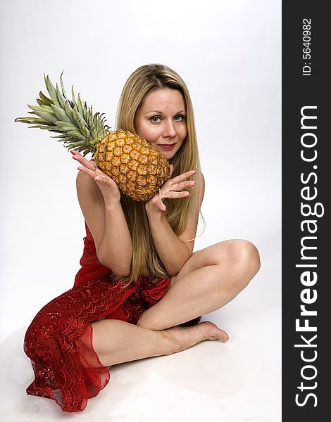 Sitting blonde long hair woman with a pineapple in her hands. Sitting blonde long hair woman with a pineapple in her hands