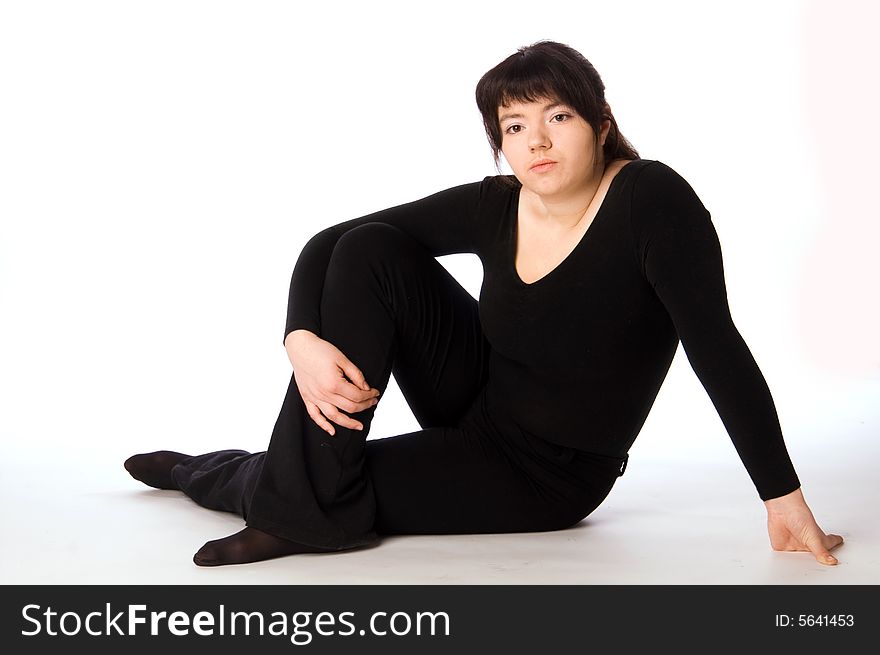 Young woman in black gym suit sitting and relaxing isolated on white