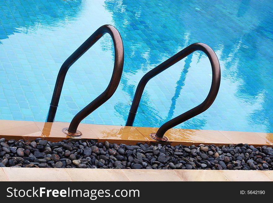 Close-up of railing and steps of a swimming pool. Close-up of railing and steps of a swimming pool.