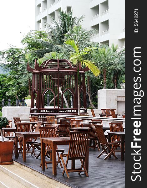 Wooden tables and chairs in an outdoor seating area of a restaurant. Wooden tables and chairs in an outdoor seating area of a restaurant.