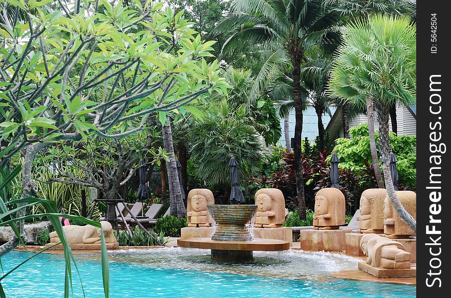 Asian statues overlooking a swimming pool at a resort in Thailand - travel and tourism.