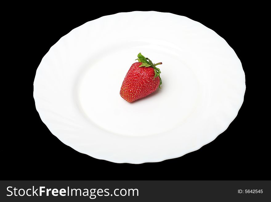 An appetizing strawberry on a white plate at thÑƒ black background. An appetizing strawberry on a white plate at thÑƒ black background