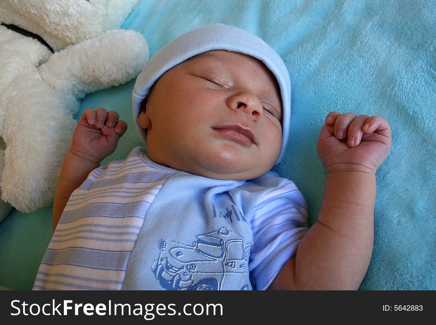 Week old baby boy on a blue blanket early in the morning. Week old baby boy on a blue blanket early in the morning