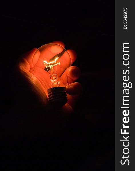 Luminous bulb in hand on black background. Luminous bulb in hand on black background