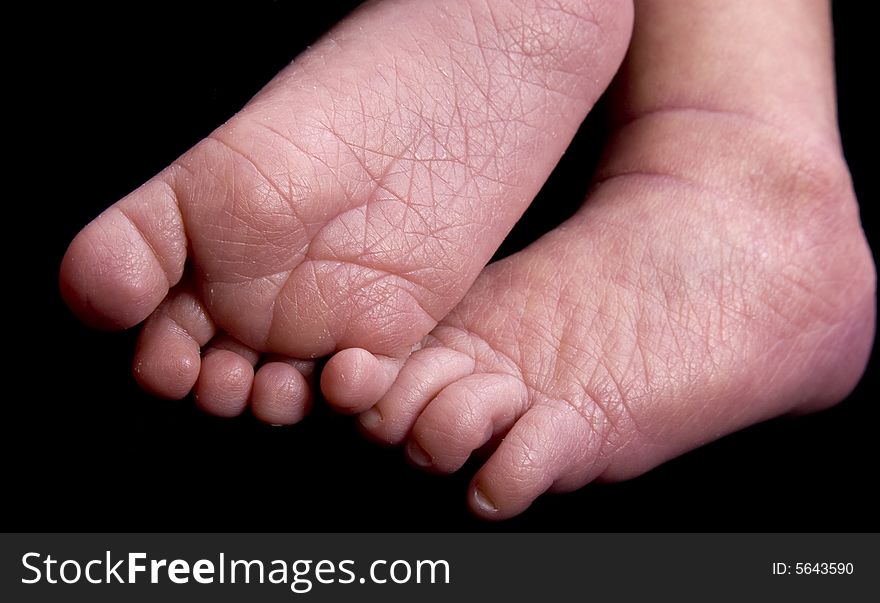 Baby feet in front of black background extended to camera