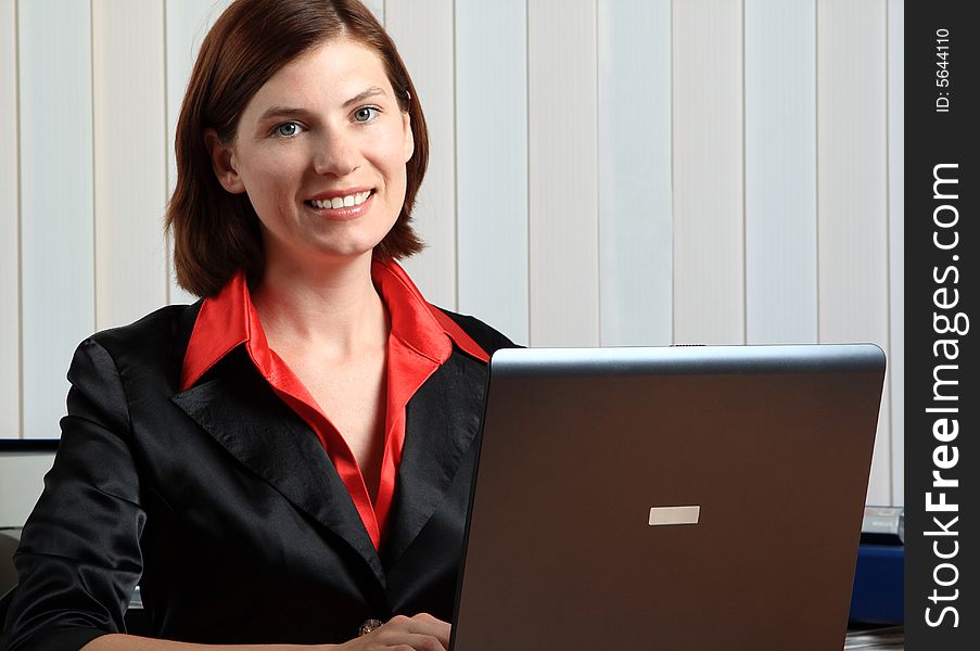 The young beautiful girl sitting works for laptop. The young beautiful girl sitting works for laptop