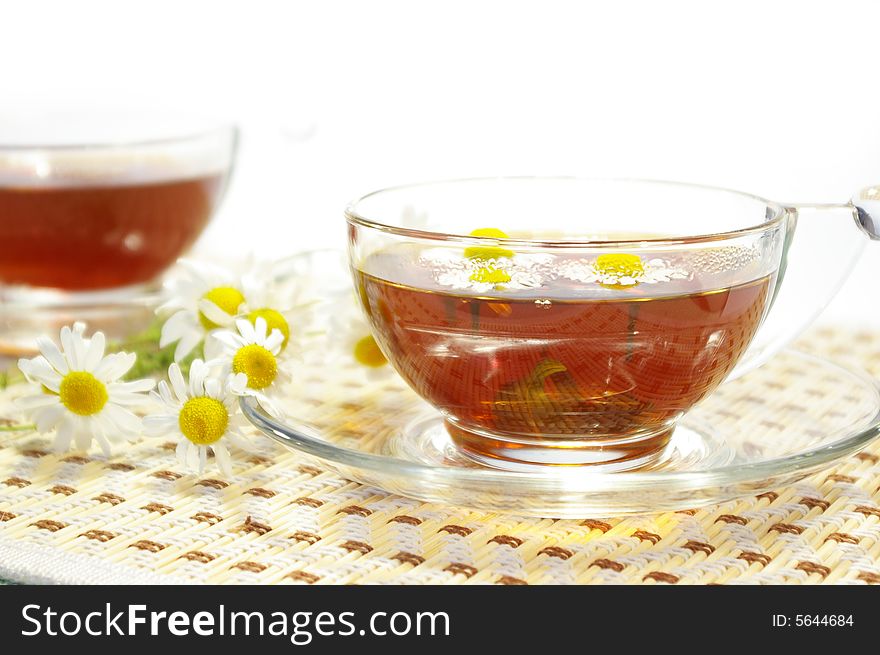 Two cups of herbal tea and chamomile blossoms