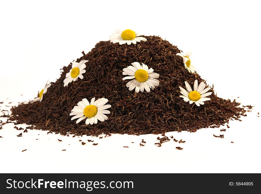 Heap of black tea and chamomile blossoms isolated on white