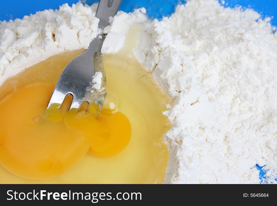 Raw egg and flower with a fork in the yolk. Raw egg and flower with a fork in the yolk