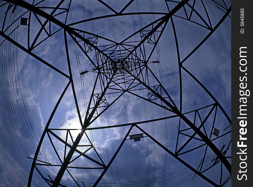 Looking from base of steel electricity pylon towards its top,backlit by sun.