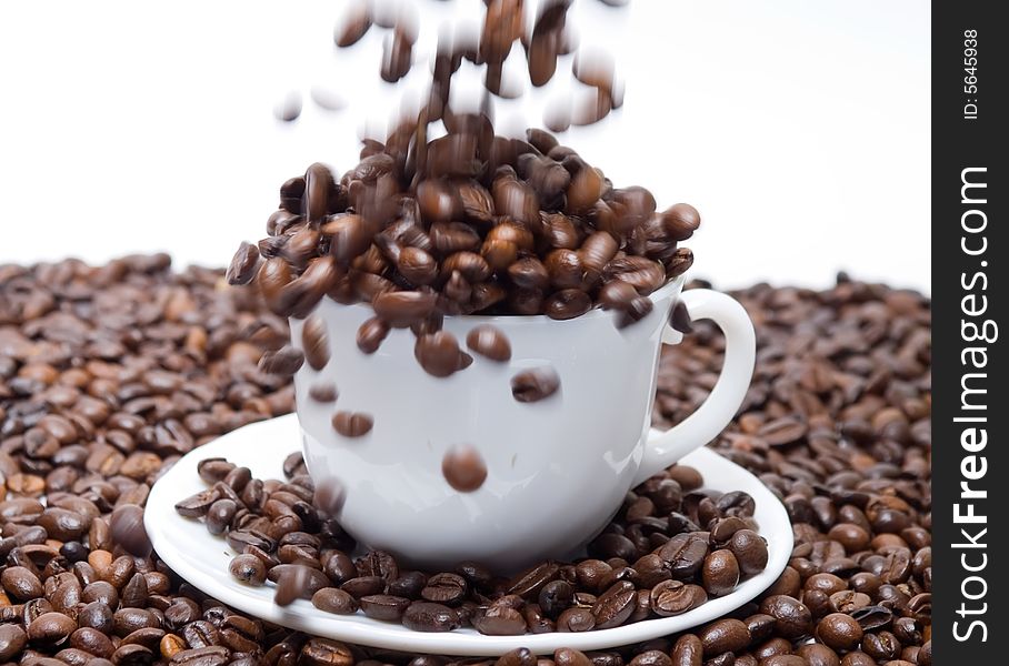 Coffee beans falling into the cup isolated at the white background