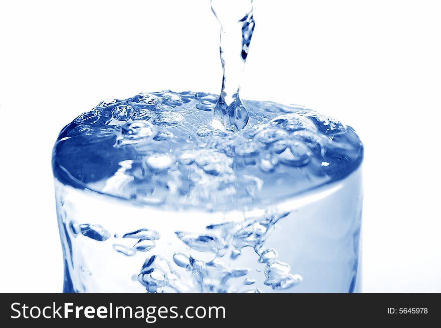 Big long drop of cold water poured into full glass (isolated on white background). Big long drop of cold water poured into full glass (isolated on white background)