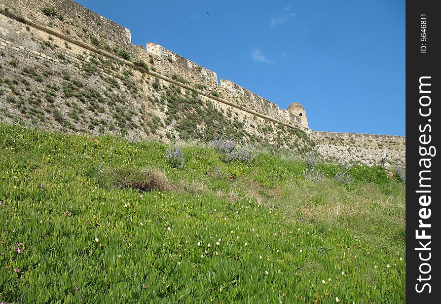 Section of ancient fortress wall, wildflowers and blue sky combine to make a beautiful, and interesting photo. Section of ancient fortress wall, wildflowers and blue sky combine to make a beautiful, and interesting photo.