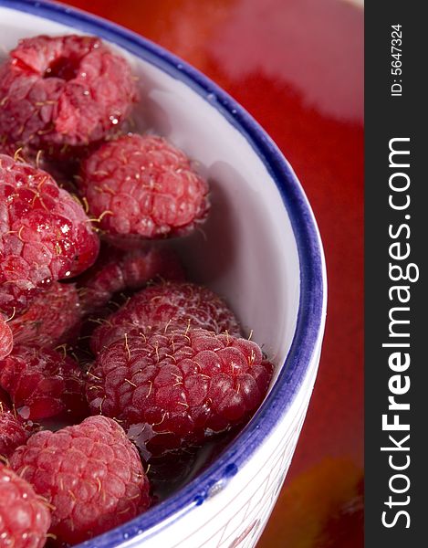 Fresh raspberries in bowl on red