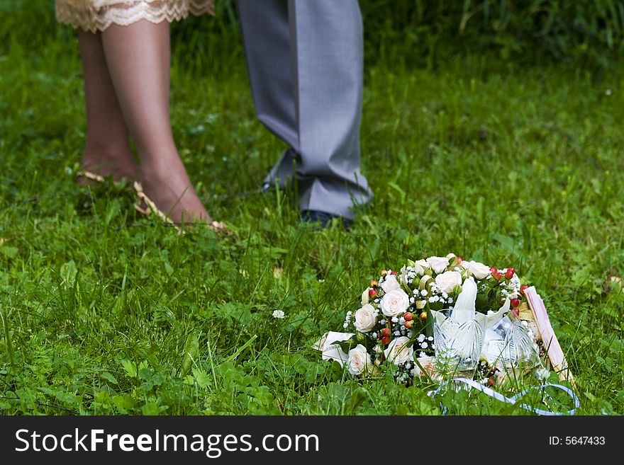 Legs of the groom and the bride and a wedding bouquet