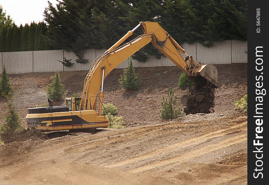 Excavator drops dirt on higher ground at job site. Excavator drops dirt on higher ground at job site.