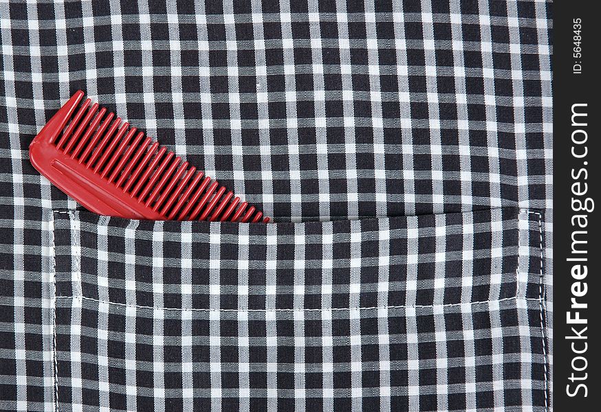 A red comb in the pocket of a checkered shirt. A red comb in the pocket of a checkered shirt.