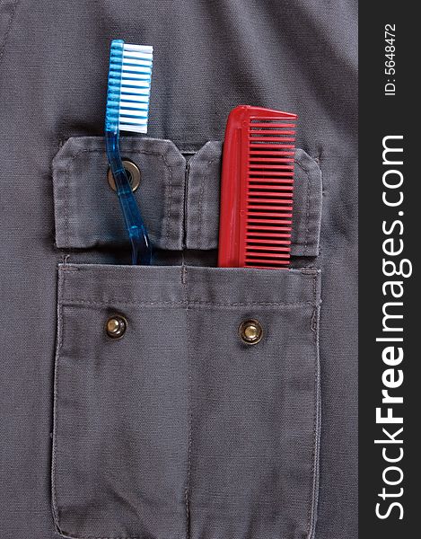 A toothbrush and a comb in the pocket of a jacket.  A travel concept.