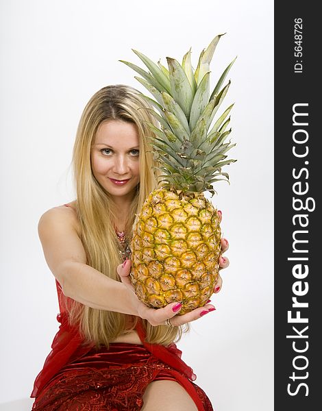 Sitting blonde long hair woman with a pineapple in her hands. Sitting blonde long hair woman with a pineapple in her hands