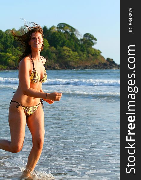 A young woman at the beach in the water. Running in the water with a bikini. Ideal vacation shot. A young woman at the beach in the water. Running in the water with a bikini. Ideal vacation shot.