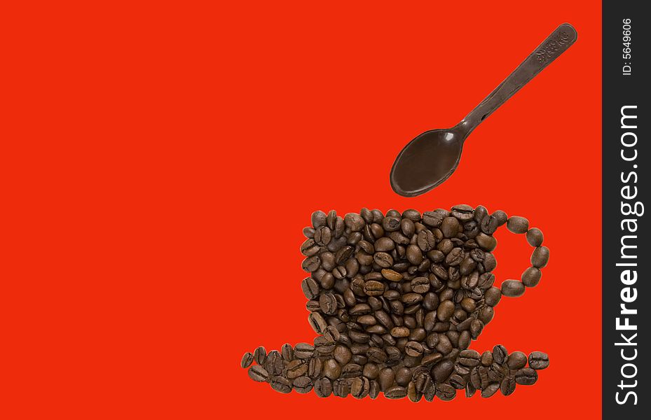 Coffee cup made of coffee beans with a chocolate spoon on top on a red background. Copy space. Clipping path of cup and spoon.