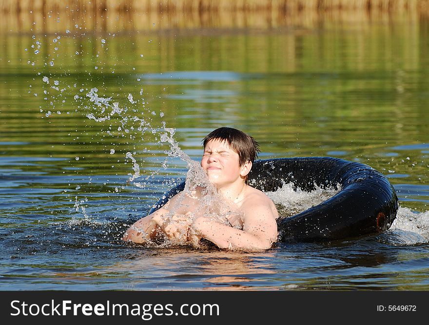 The boy in a tube making splashes ina small lake late afternoon (Lithuania).