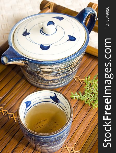 Close up of a cup of green tea and teapot on a bamboo tea tray. Focus on the tea. Close up of a cup of green tea and teapot on a bamboo tea tray. Focus on the tea.