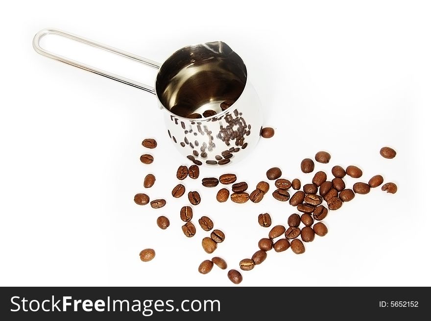 Metallic ibrik with reflected coffee beans and ground coffee