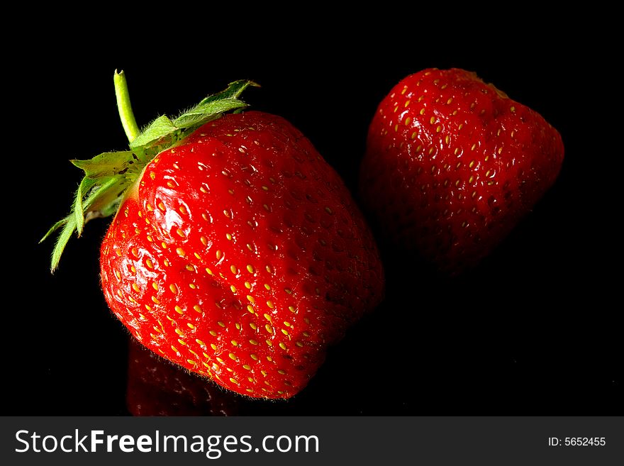 Two strawberries on black background