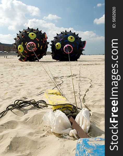 Two black round shapes kites on a beach with blue sky. Two black round shapes kites on a beach with blue sky