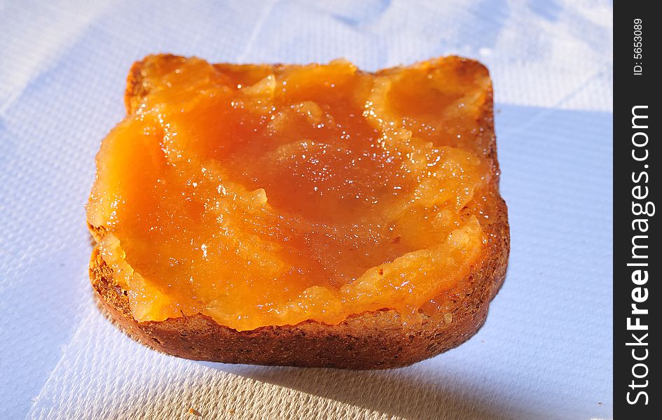 A snack with a rusk biscuit covered with apple jam. Natural sunset light plus flash light. Close shot. A snack with a rusk biscuit covered with apple jam. Natural sunset light plus flash light. Close shot.