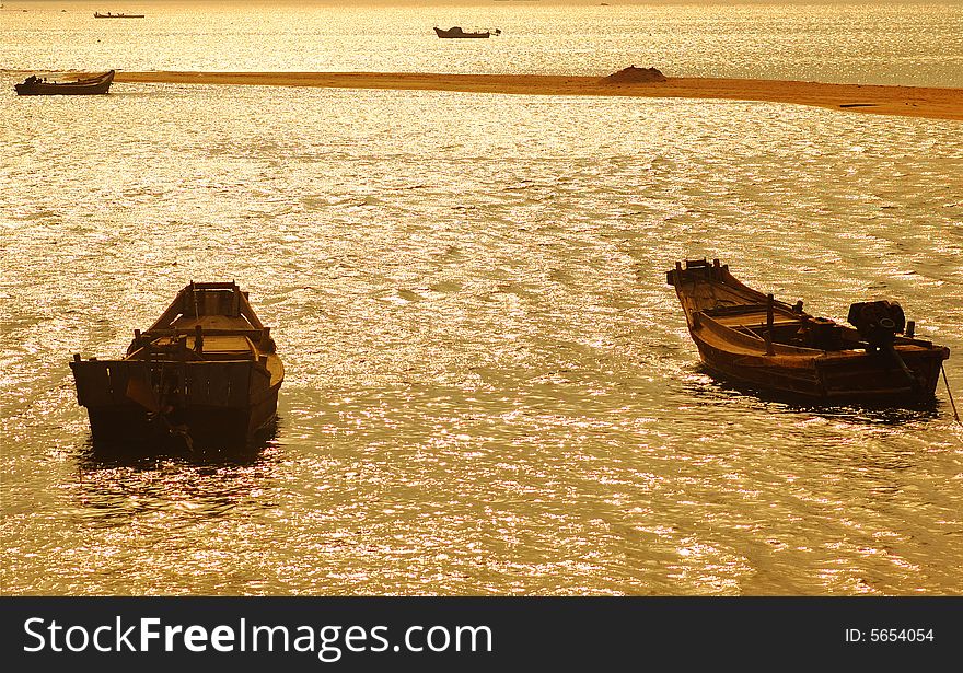 The fishing boat under the setting sun, the golden color sea water, composes a beautiful landscape painting. Photography in the Weihai Shandong China